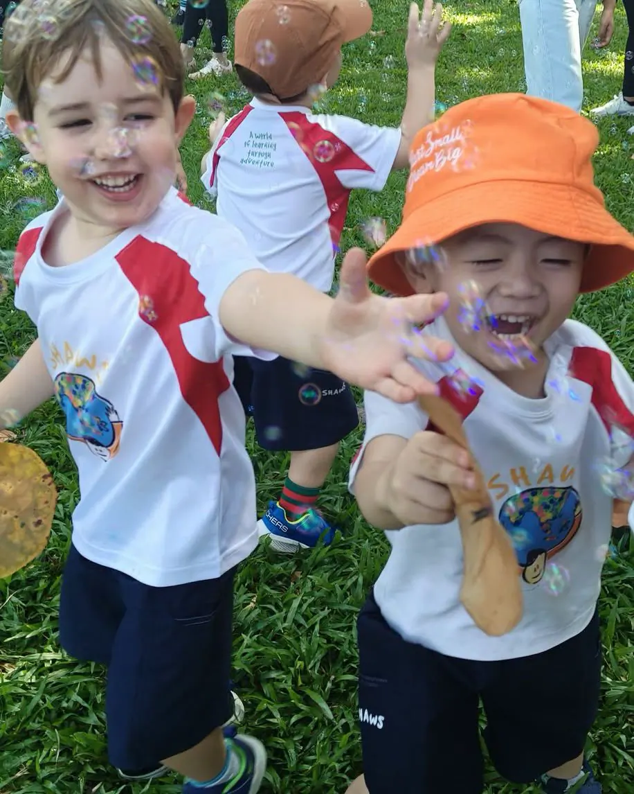 Two Shaws Preschool boys covered in paint, laughing, during an outdoor messy-play session