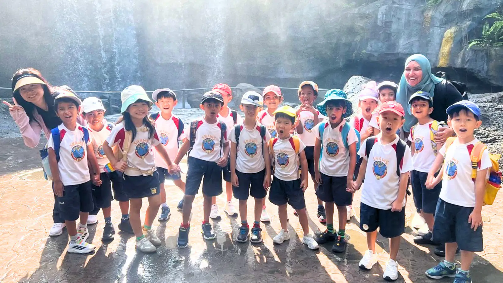 A Shaws Preschool class and their teachers standing together in front of a waterfall on a school excursion