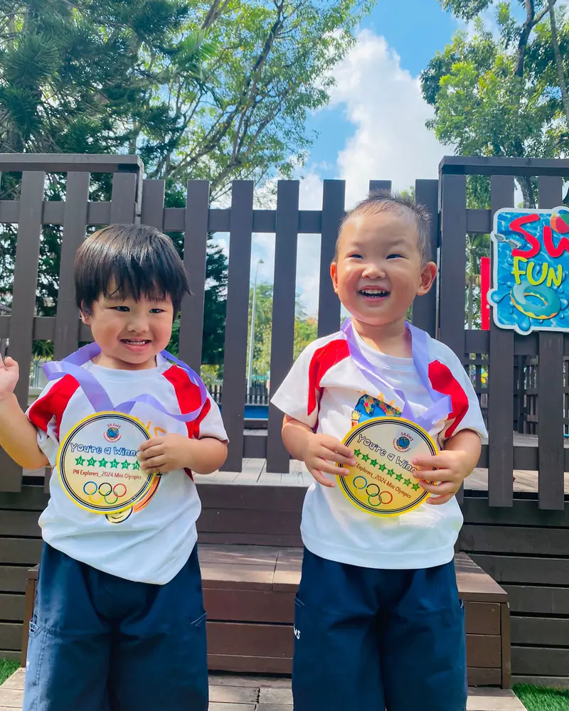 Two Shaws toddlers holding up the medals they were awarded on Sports Day