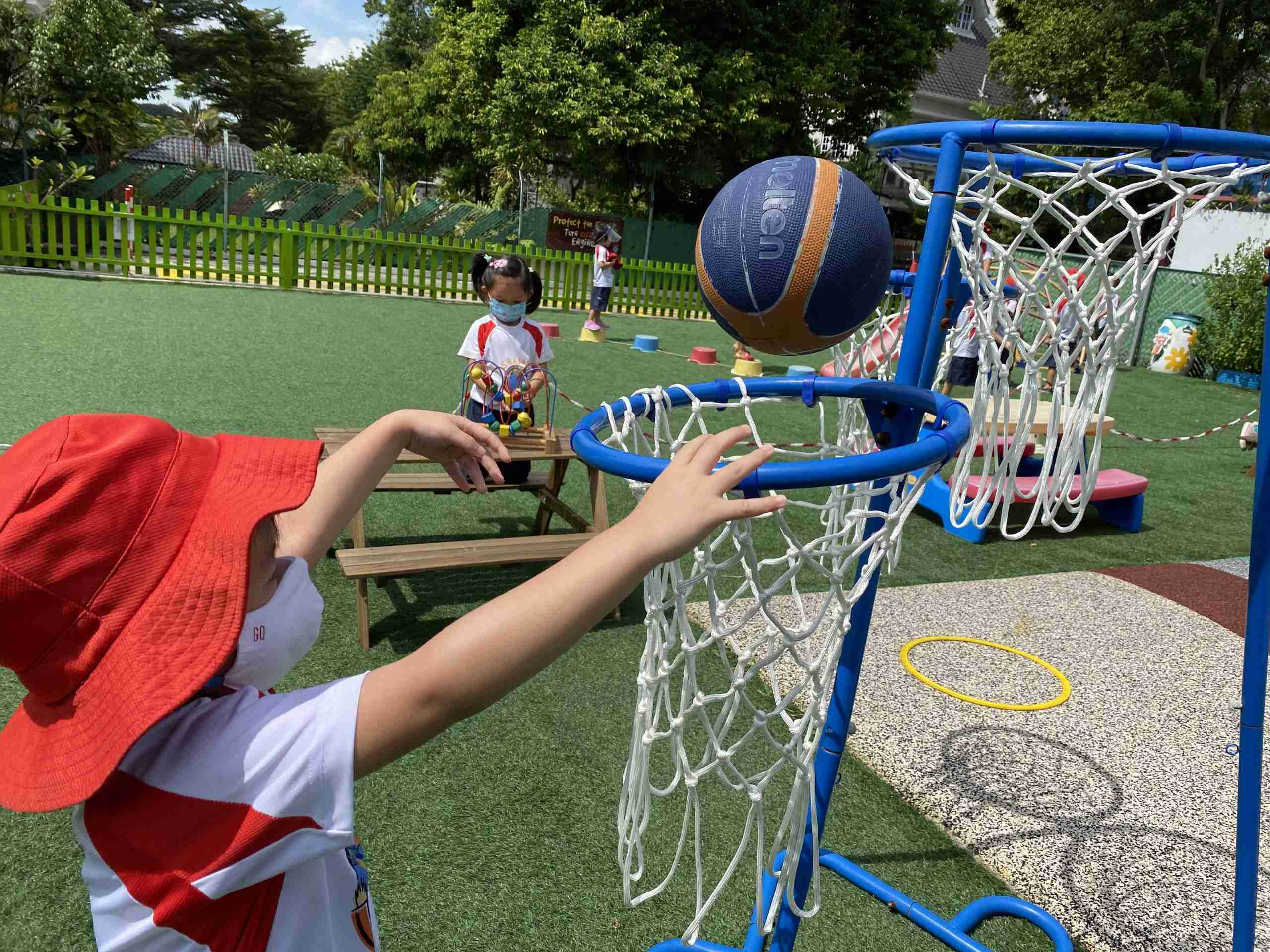 preschooler throwing basketball into a hoop